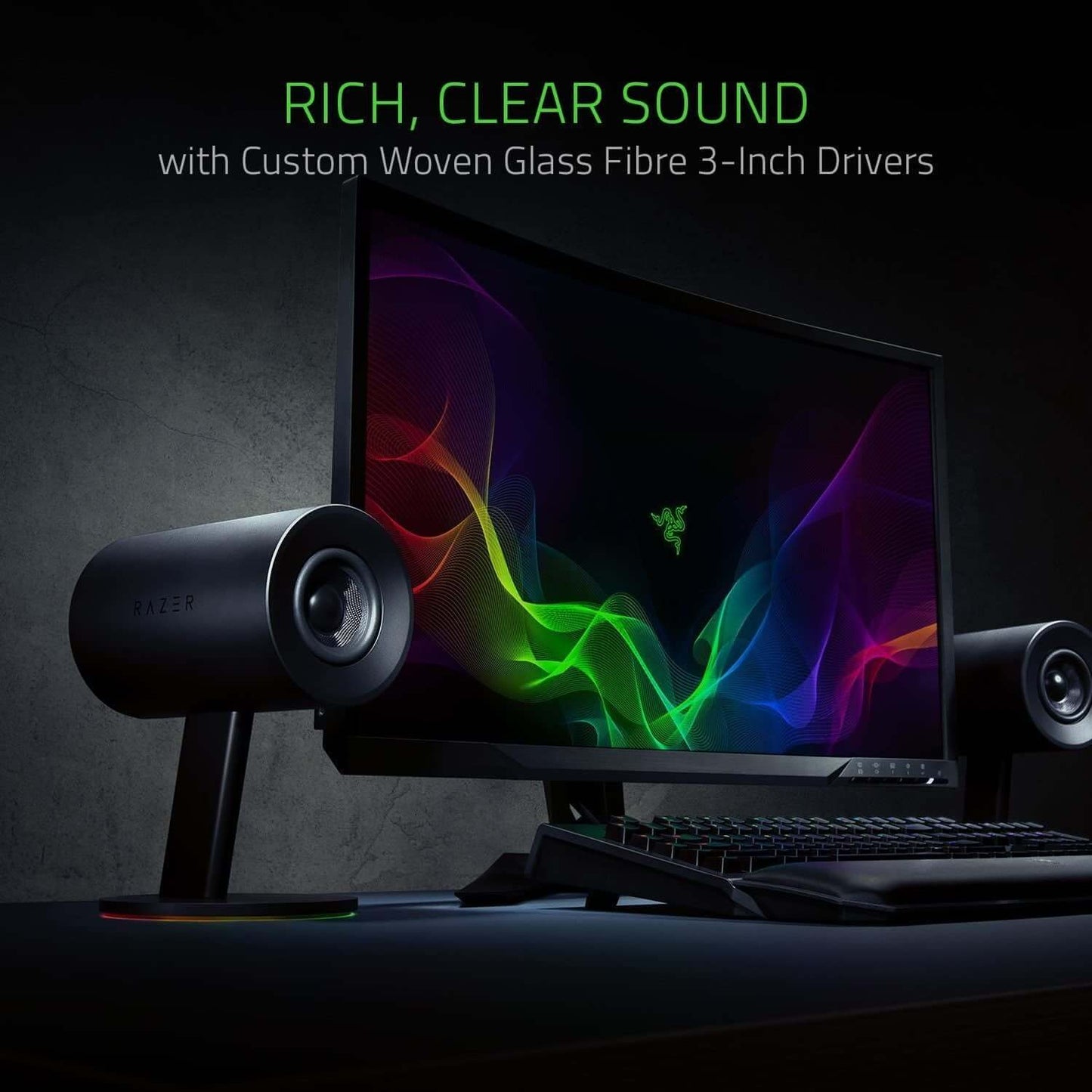 Razer Nommo Chroma gaming speakers showcasing rich sound with custom 3-inch woven glass fiber drivers beside a monitor.