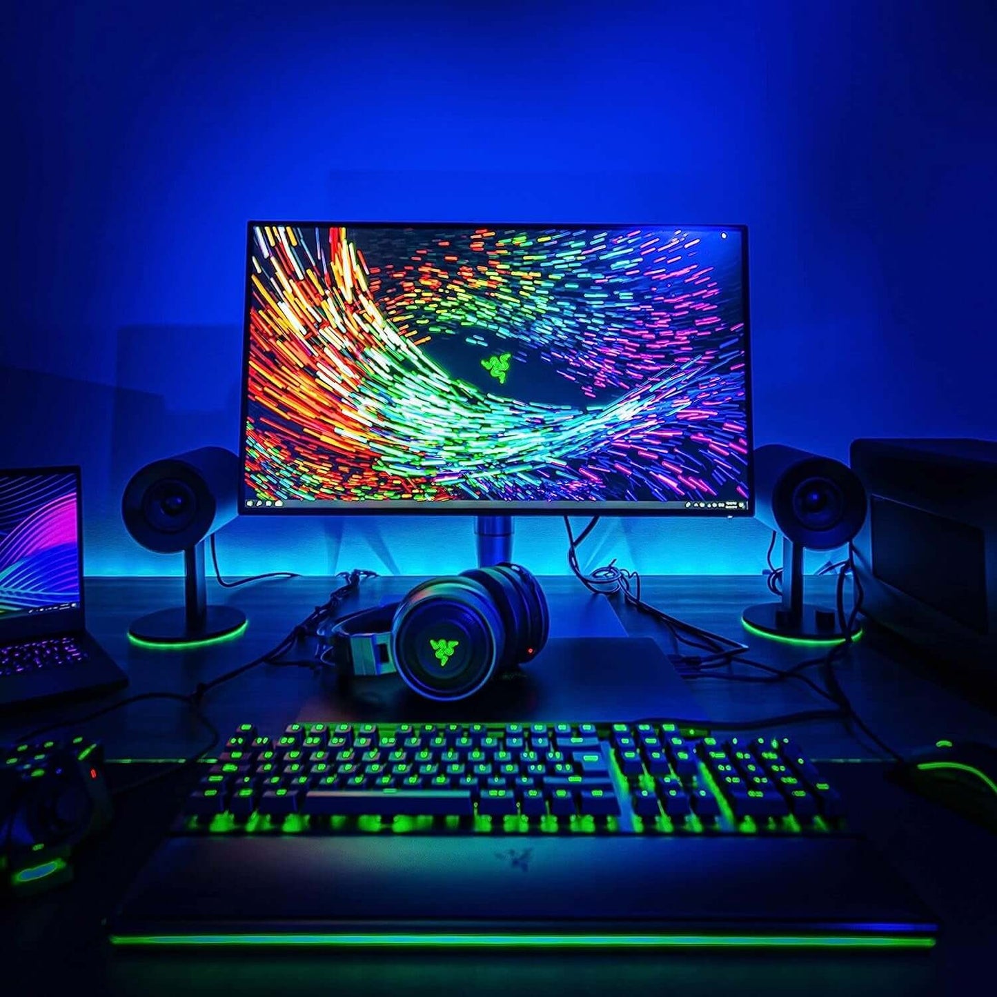 gaming setup with Razer peripherals, vibrant RGB lighting, and a colorful monitor display